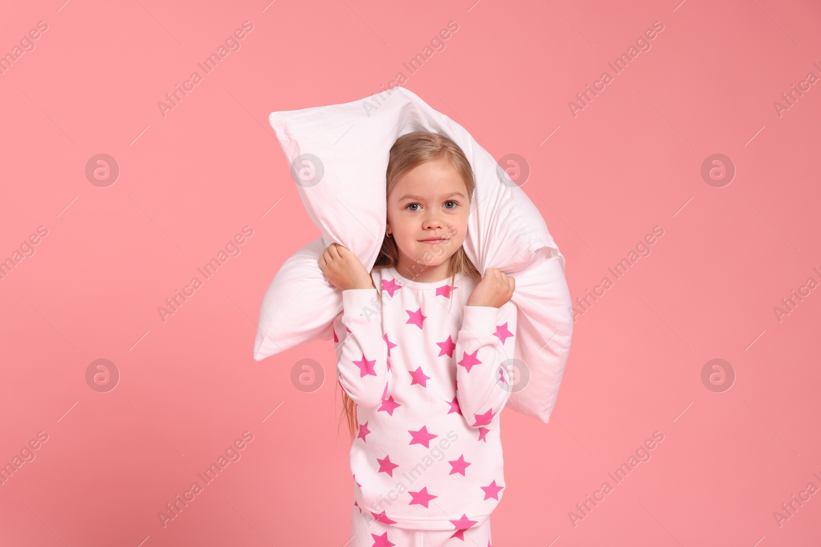 Cute little girl in pajamas with pillow on pink background Photo of Cute little girl in pajamas with pillow on pink background