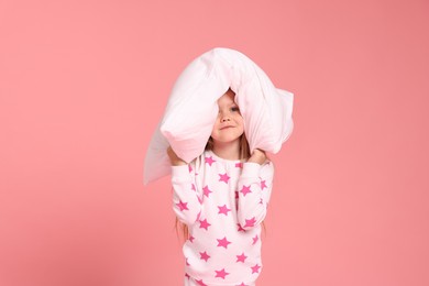 Photo of Cute little girl in pajamas with pillow on pink background