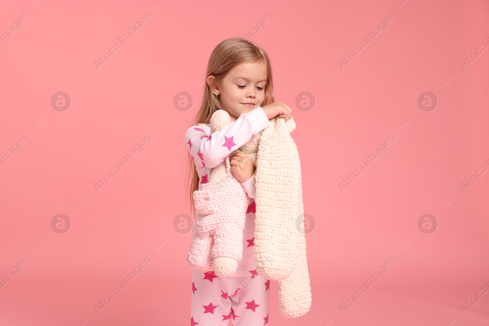 Cute little girl in pajamas with toy bunny on pink background Photo of Cute little girl in pajamas with toy bunny on pink background