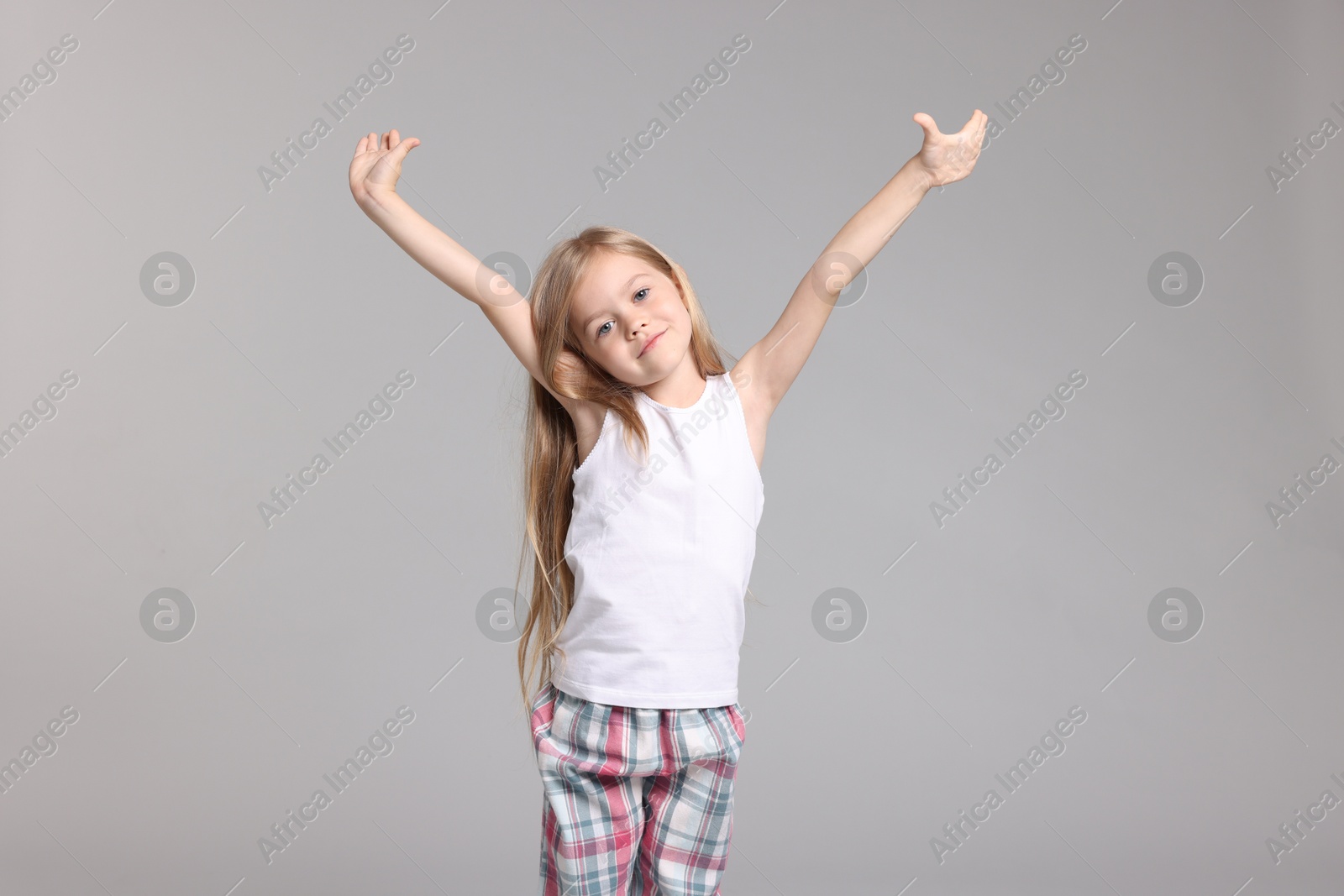 Cute little girl in pajamas on grey background Photo of Cute little girl in pajamas on grey background