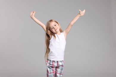 Photo of Cute little girl in pajamas on grey background