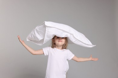 Photo of Cute little girl in pajamas with pillow on grey background