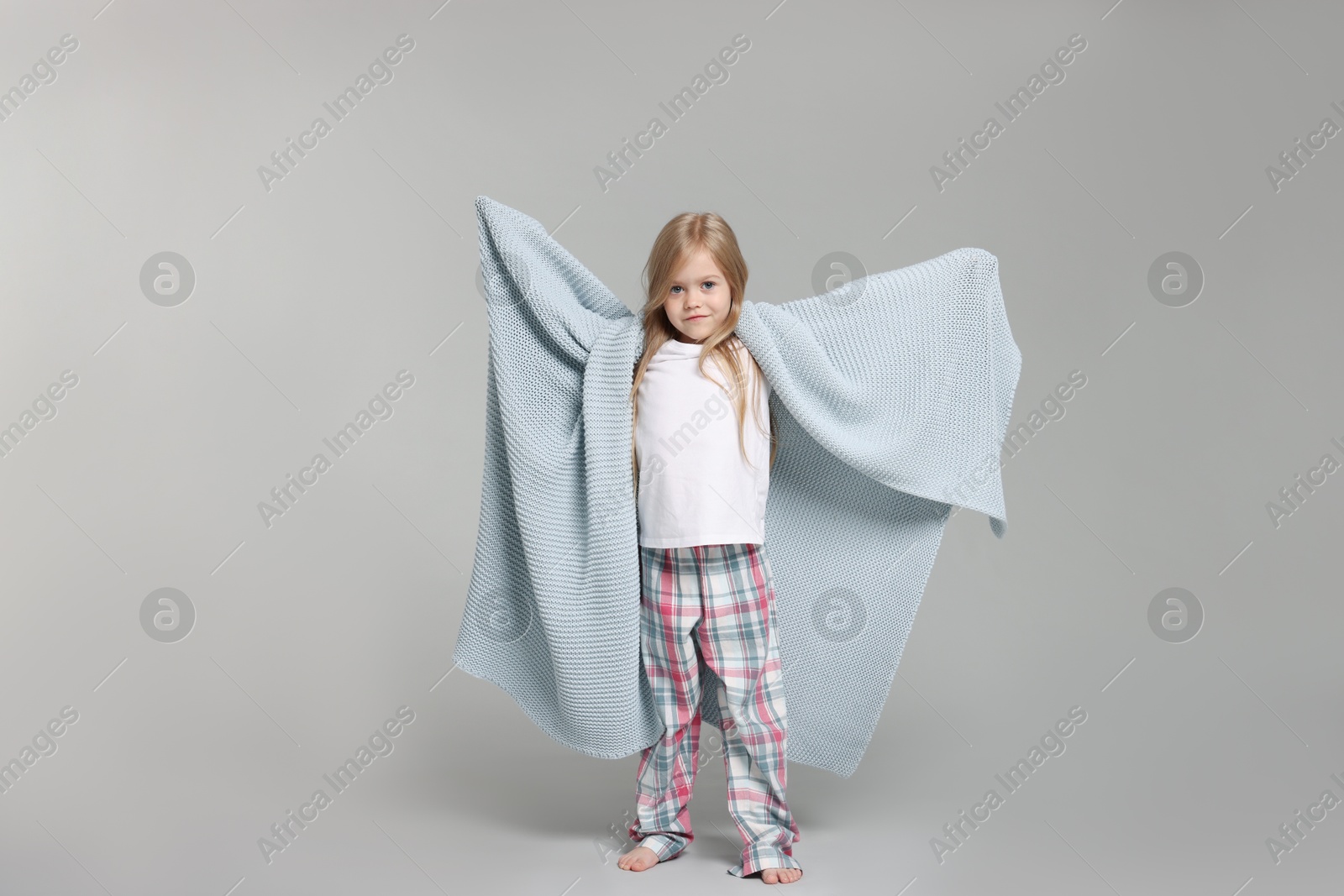 Cute little girl in pajamas with plaid on grey background Photo of Cute little girl in pajamas with plaid on grey background