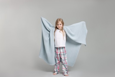 Photo of Cute little girl in pajamas with plaid on grey background
