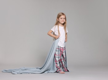 Photo of Cute little girl in pajamas with plaid on grey background