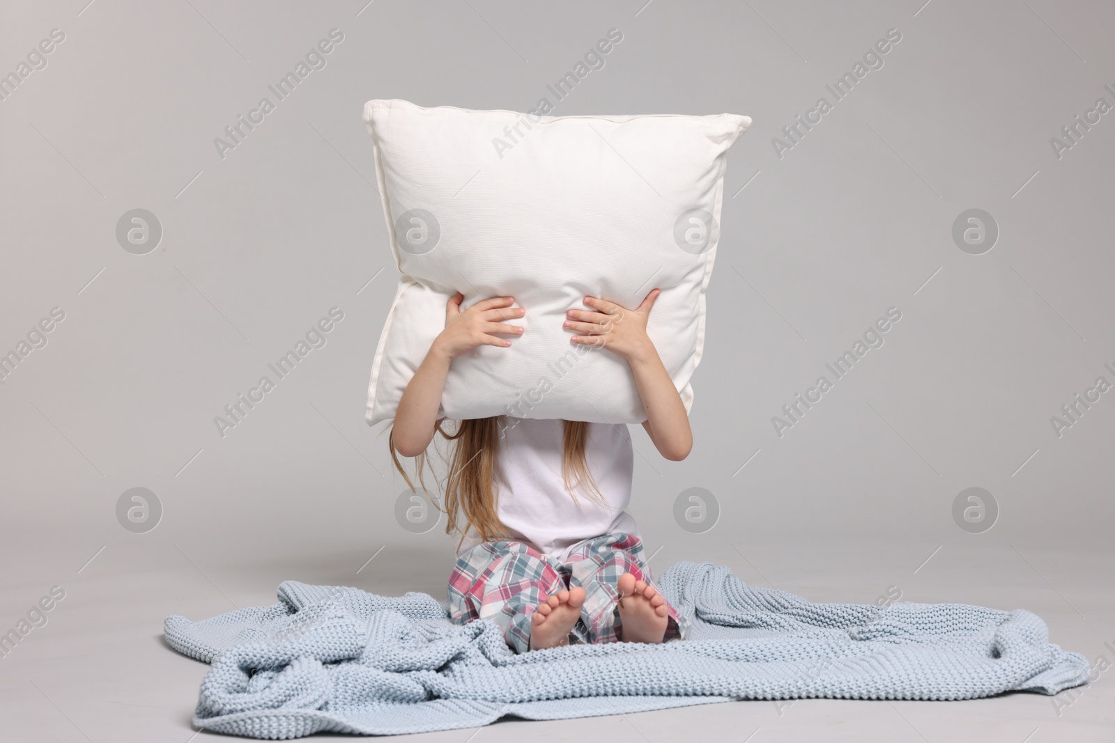 Cute little girl in pajamas with pillow and plaid on grey background Photo of Cute little girl in pajamas with pillow and plaid on grey background
