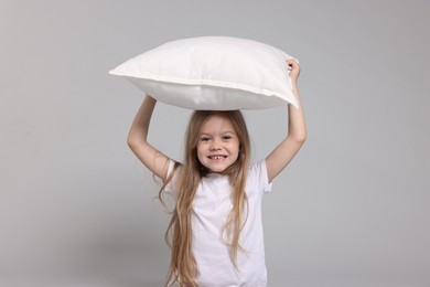 Photo of Cute little girl in pajamas with pillow on grey background