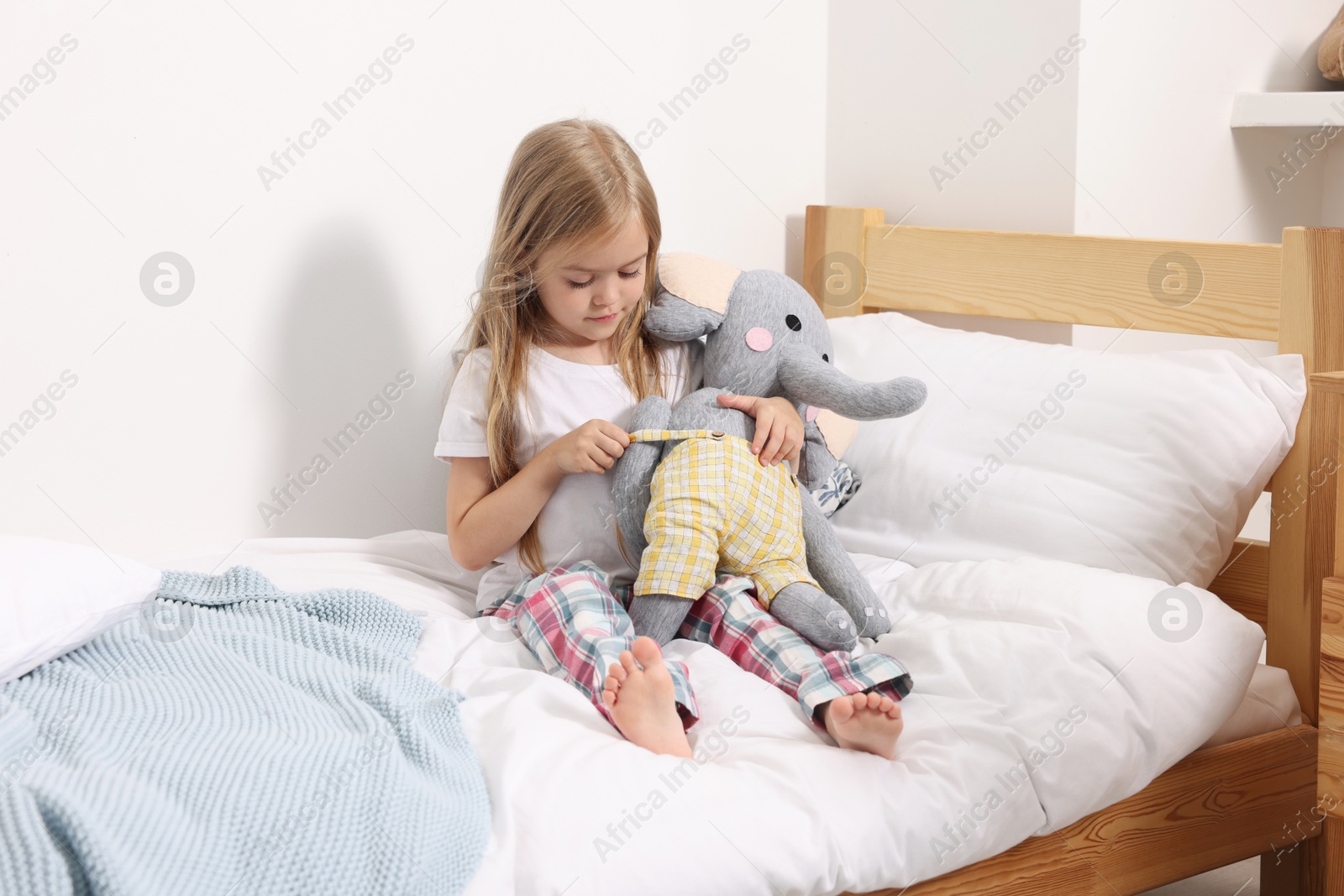 Little girl with toy elephant in bed at home Photo of Little girl with toy elephant in bed at home