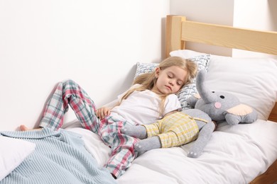 Photo of Little girl with toy elephant in bed at home