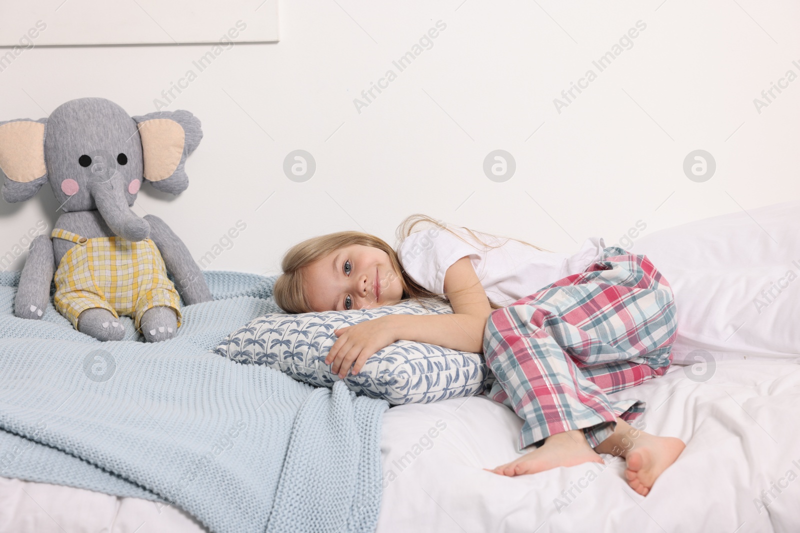 Little girl in cute pajamas lying on bed at home Photo of Little girl in cute pajamas lying on bed at home