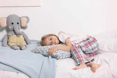 Photo of Little girl in cute pajamas lying on bed at home