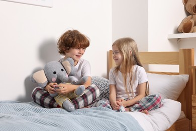 Photo of Cute children with toy elephant on bed at home