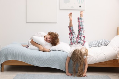 Photo of Happy children having fun on bed at home