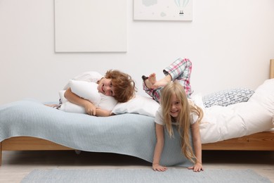 Photo of Happy children having fun on bed at home