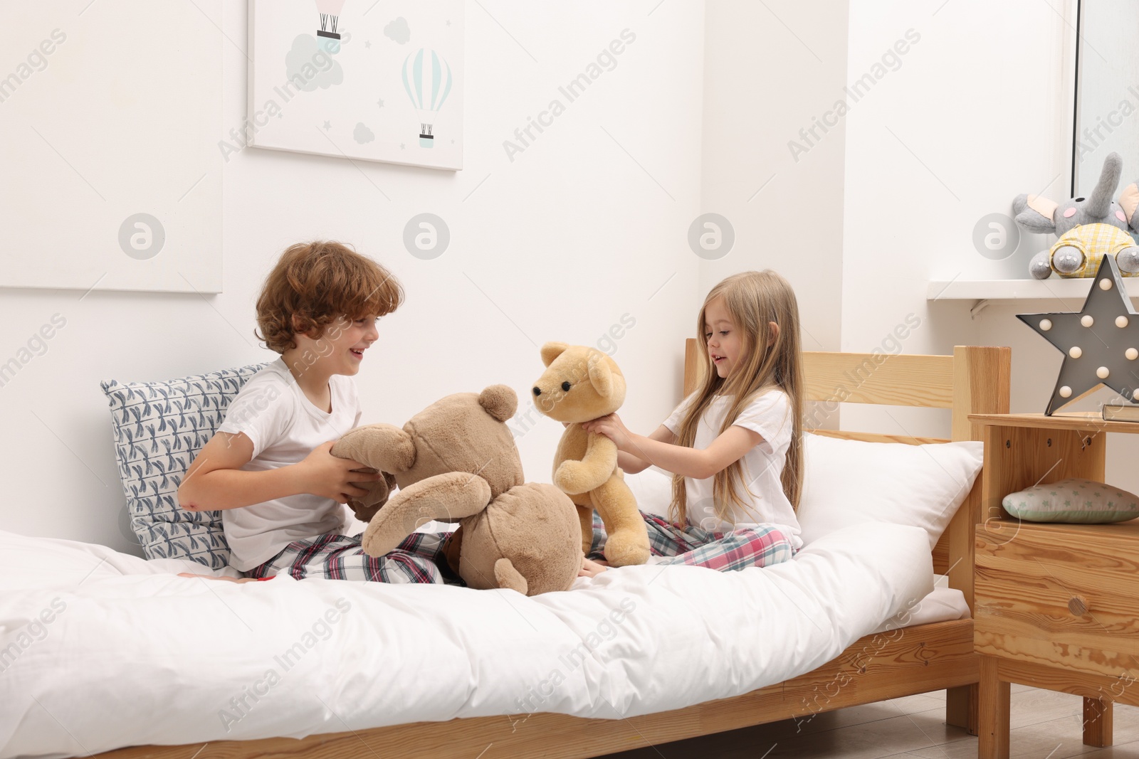 Photo of Cute children with teddy bears on bed at home