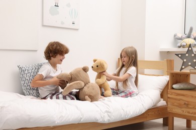 Photo of Cute children with teddy bears on bed at home