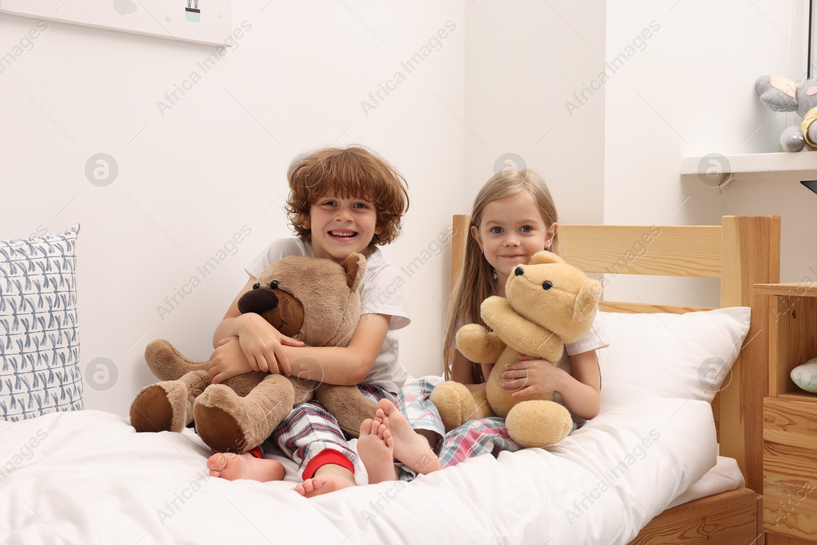Photo of Cute children with teddy bears on bed at home