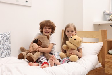 Photo of Cute children with teddy bears on bed at home