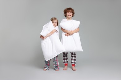 Photo of Cute little children in pajamas with pillows on grey background