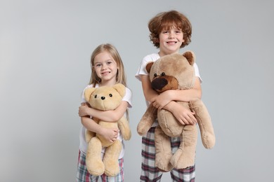 Photo of Cute little children in pajamas with teddy bears on grey background