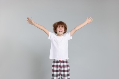 Photo of Cute little boy in pajamas on grey background
