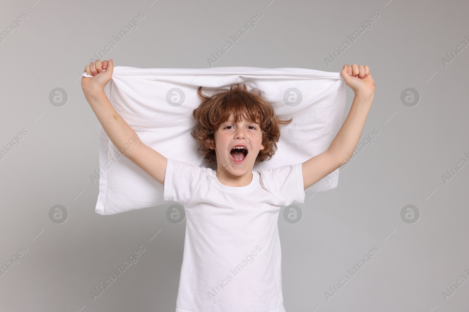 Cute little boy in pajamas with pillow on grey background Photo of Cute little boy in pajamas with pillow on grey background