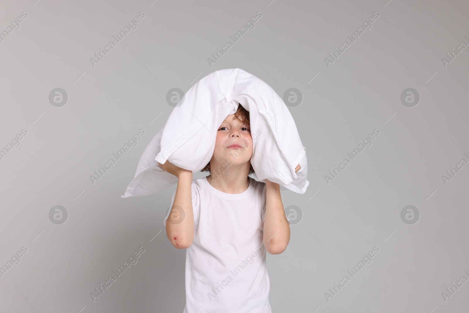 Cute little boy in pajamas with pillow on grey background Photo of Cute little boy in pajamas with pillow on grey background