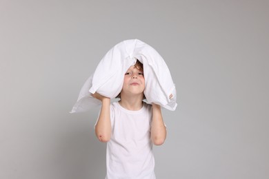 Photo of Cute little boy in pajamas with pillow on grey background