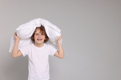 Photo of Cute little boy in pajamas with pillow on grey background. Space for text