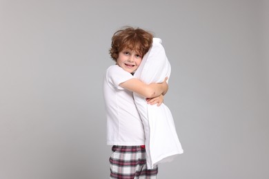 Photo of Cute little boy in pajamas with pillow on grey background