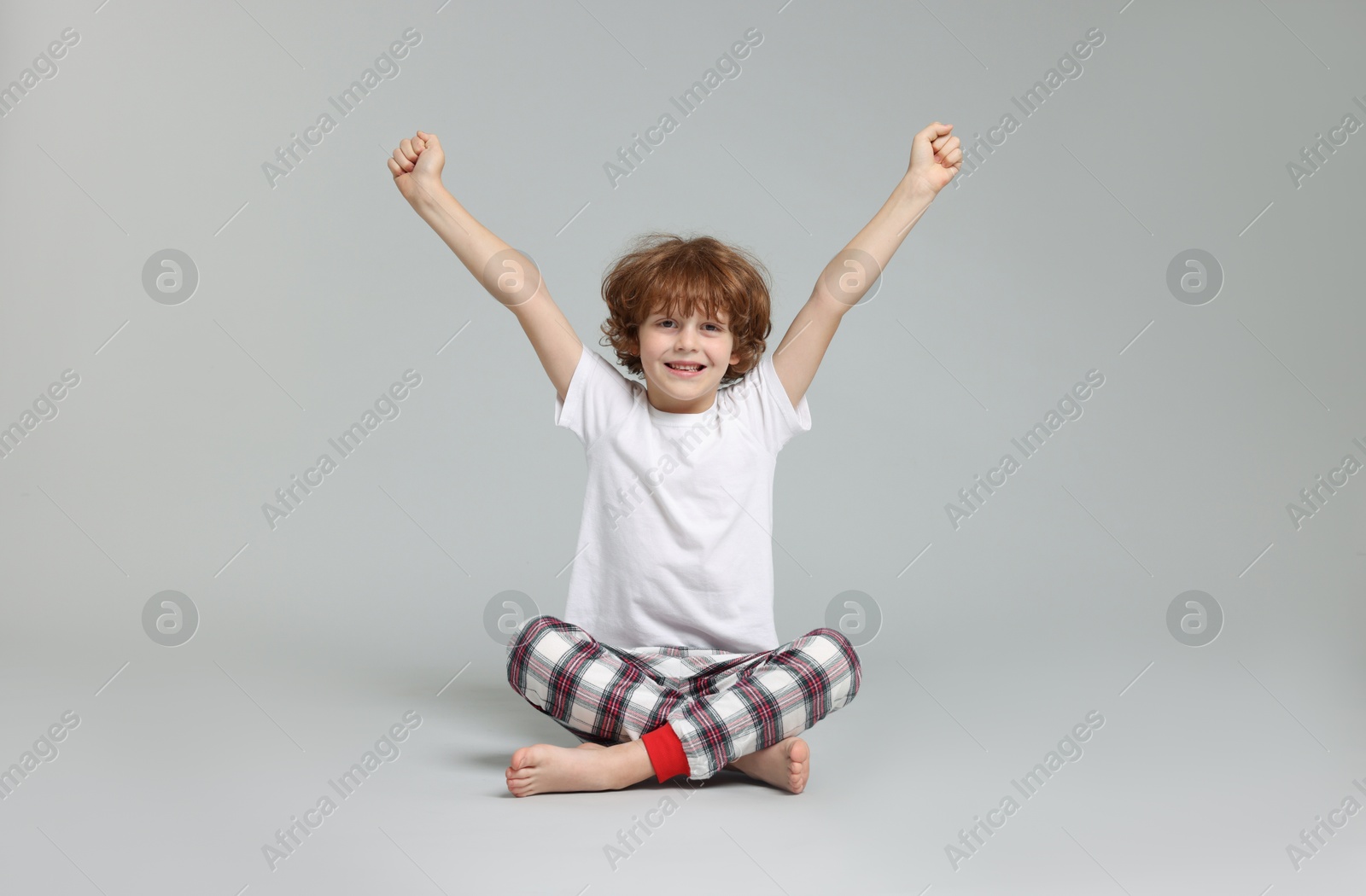 Photo of Cute little boy in pajamas on grey background