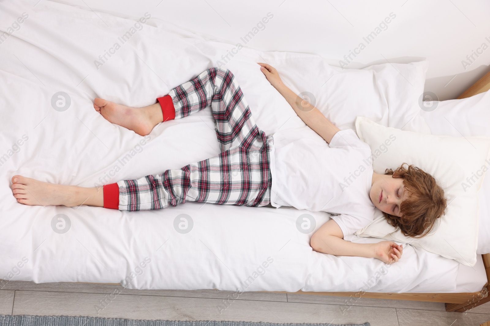 Little boy sleeping in bed at home, above view Photo of Little boy sleeping in bed at home, above view