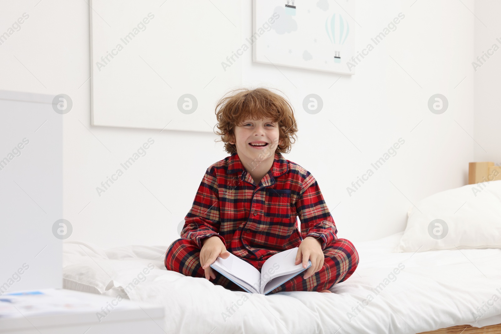 Little boy with book on bed at home Photo of Little boy with book on bed at home