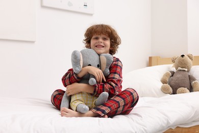 Photo of Little boy with toy elephant on bed at home