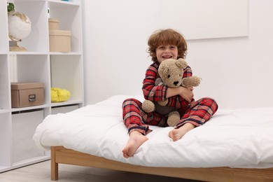 Photo of Little boy with teddy bear on bed at home