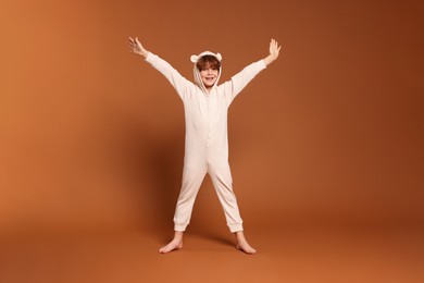 Photo of Cute little boy in pajamas on brown background