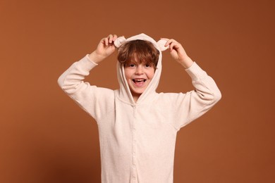 Photo of Cute little boy in pajamas on brown background