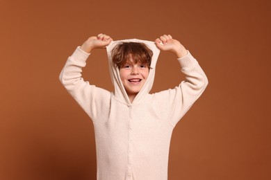 Photo of Cute little boy in pajamas on brown background