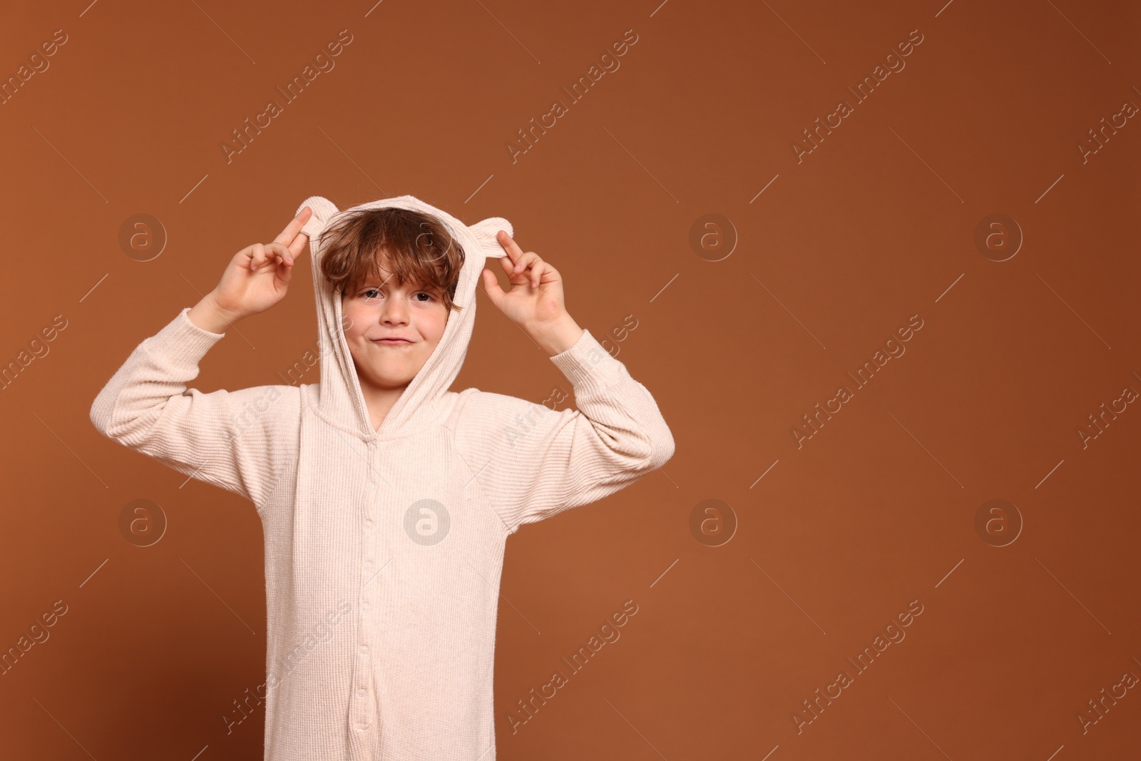 Cute little boy in pajamas on brown background. Space for text Photo of Cute little boy in pajamas on brown background. Space for text