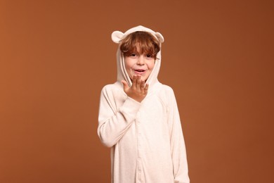 Photo of Cute little boy in pajamas on brown background
