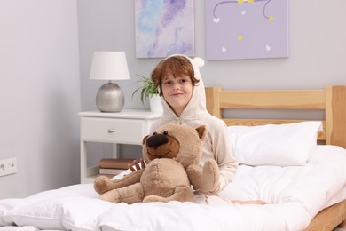 Photo of Little boy with teddy bear on bed at home