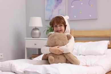 Photo of Little boy with teddy bear on bed at home