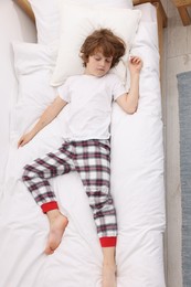 Photo of Cute little boy sleeping on bed at home, top view