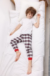Photo of Cute little boy sleeping on bed at home, top view
