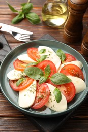 Photo of Tasty salad Caprese served on wooden table, above view