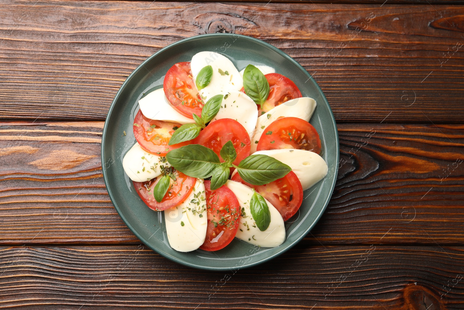 Tasty salad Caprese with mozzarella, tomatoes, basil and spices on wooden table, top view Photo of Tasty salad Caprese with mozzarella, tomatoes, basil and spices on wooden table, top view