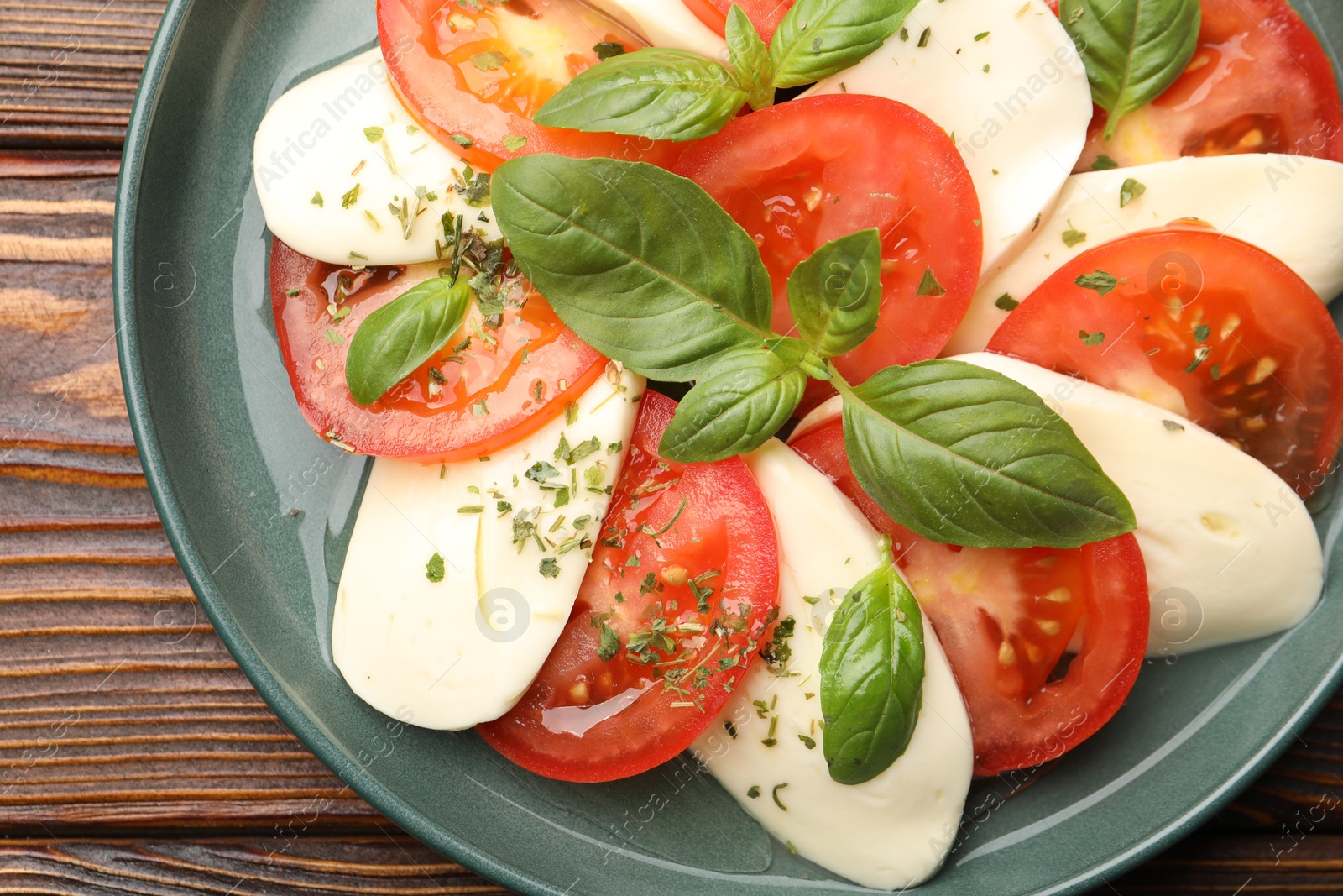 Tasty salad Caprese with mozzarella, tomatoes, basil and spices on wooden table, top view Photo of Tasty salad Caprese with mozzarella, tomatoes, basil and spices on wooden table, top view
