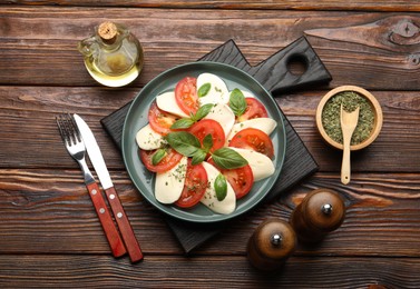 Photo of Tasty salad Caprese served on wooden table, flat lay