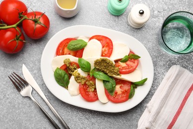 Photo of Tasty salad Caprese served with pesto sauce on grey table, flat lay
