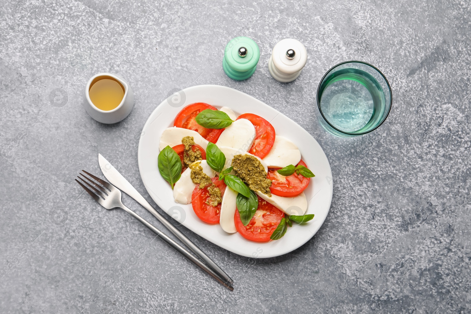 Tasty salad Caprese served with pesto sauce on grey table, flat lay Photo of Tasty salad Caprese served with pesto sauce on grey table, flat lay